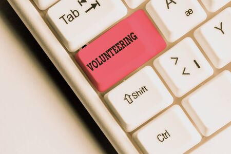 Word writing text Volunteering. Business photo showcasing Provide services for no financial gain Willingly Oblige White pc keyboard with empty note paper above white background key copy spaceの写真素材