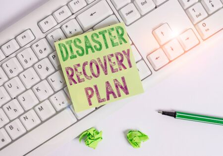 Writing note showing Disaster Recovery Plan. Business concept for having backup measures against dangerous situation Green note paper with pencil on white background and pc keyboardの写真素材