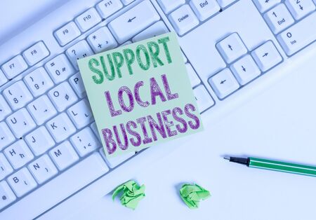 Writing note showing Support Local Business. Business concept for increase investment in your country or town Green note paper with pencil on white background and pc keyboardの写真素材