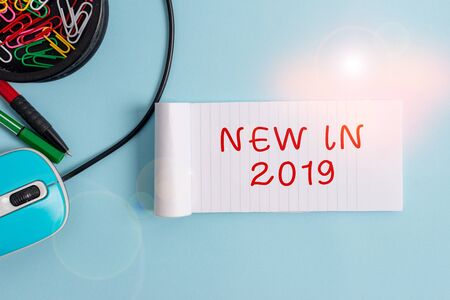 Handwriting text New In 2019. Conceptual photo what will be expecting or new creation for the year 2019 Notebook and writing equipment with computer mouse above pastel backdropの写真素材