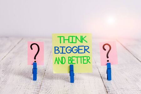 Conceptual hand writing showing Think Bigger And Better. Concept meaning no Limits be Open minded Positivity Big Picture Crumbling sheet with paper clips placed on the wooden tableの写真素材