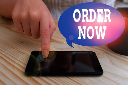 Text sign showing Order Now. Business photo text the activity of asking for goods or services from a company woman using smartphone office supplies technological devices inside homeの写真素材