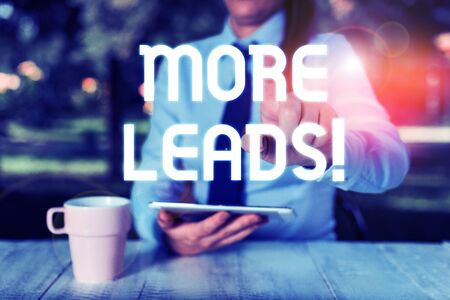 Text sign showing More Leads. Business photo text initiation of consumer interest or enquiry into product Female business person sitting by table and holding mobile phoneの写真素材