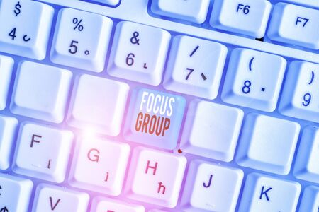 Writing note showing Focus Group. Business concept for showing assembled to participate in discussion about something White pc keyboard with note paper above the white backgroundの写真素材