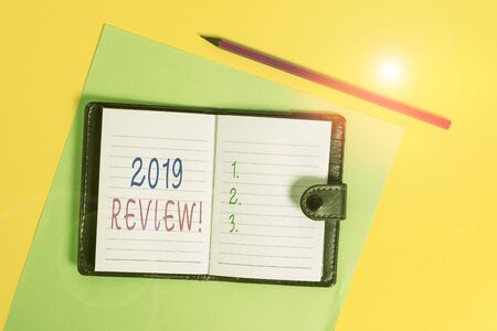 Text sign showing 2019 Review. Business photo showcasing remembering past year events main actions or good shows Dark leather private locked diary striped sheets marker colored backgroundの写真素材