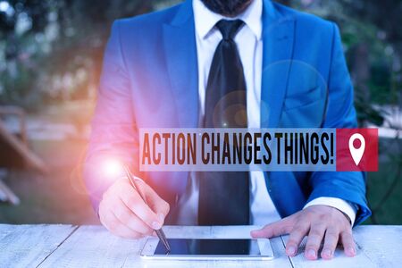 Word writing text Action Changes Things. Business photo showcasing start doing something against problem resolve or achieve it Businessman holds pen and points into copy spaceの写真素材