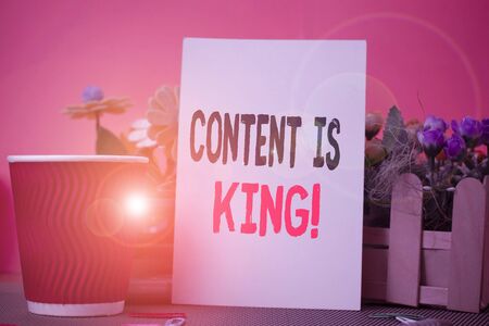 Word writing text Content Is King. Business photo showcasing marketing focused growing visibility non paid search results Flowers and stationary plus plain sheet with paper big cup above a tableの写真素材