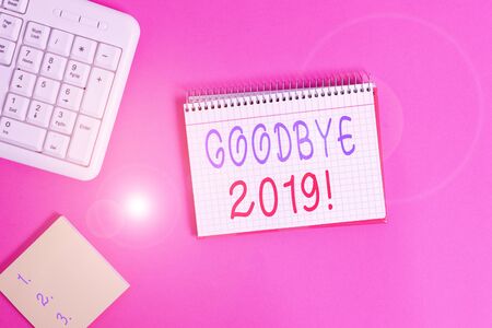 Text sign showing Goodbye 2019. Business photo showcasing express good wishes when parting or at the end of last year Writing equipments and computer stuffs placed above classic wooden tableの写真素材