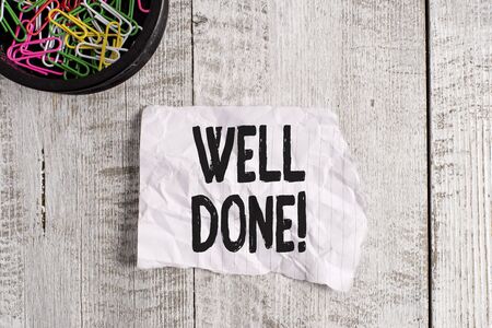 Conceptual hand writing showing Well Done. Concept meaning used praising demonstrating or group for something have done good way Wrinkle paper and cardboard placed above wooden backgroundの写真素材