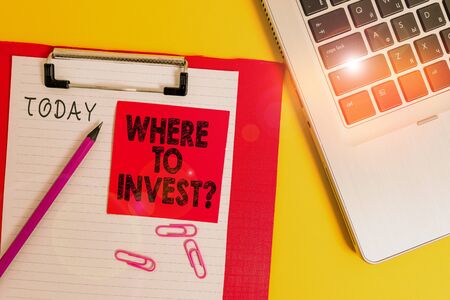 Conceptual hand writing showing Where To Invest Question. Concept meaning asking about where put money into financial schemes or shares Metallic laptop clipboard paper sheet pencil colored backgroundの写真素材