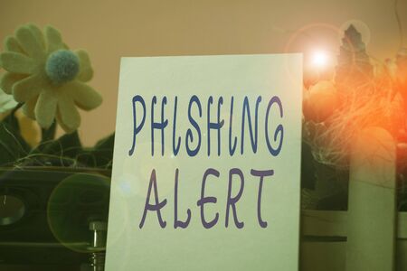 Handwriting text Phishing Alert. Conceptual photo aware to fraudulent attempt to obtain sensitive information Flowers and writing equipments plus plain sheet above textured backdropの写真素材