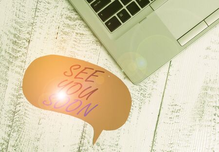 Writing note showing See You Soon. Business concept for used for saying goodbye to someone and going to meet again soon Close view laptop blank speech bubble downwards lying vintage tableの写真素材