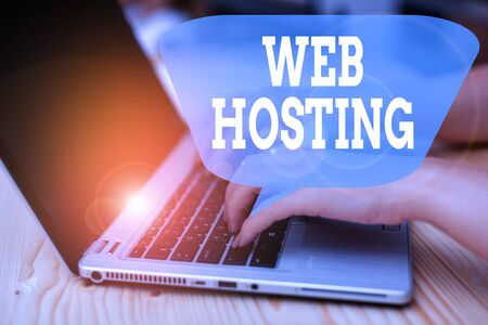 Conceptual hand writing showing Web Hosting. Concept meaning The activity of providing storage space and access for websites woman with laptop smartphone and office supplies technologyの写真素材