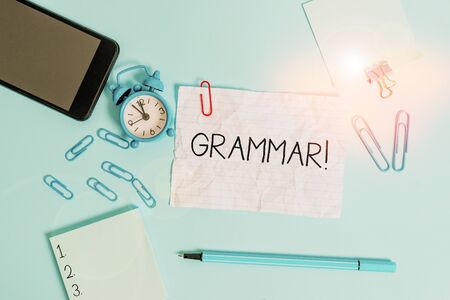 Handwriting text Grammar. Conceptual photo whole system structure language syntax and morphology Alarm clock clips notepad smartphone rubber band marker colored backgroundの写真素材