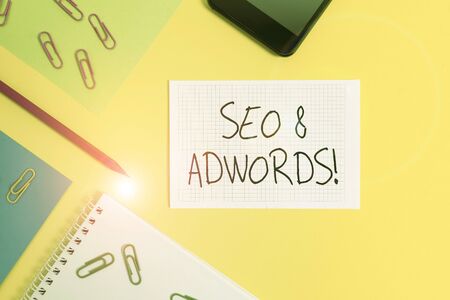 Writing note showing Seo And Adwords. Business concept for they are main tools components of Search Engine Marketing Paper sheets square notebook pencil clips smartphone colored backgroundの写真素材