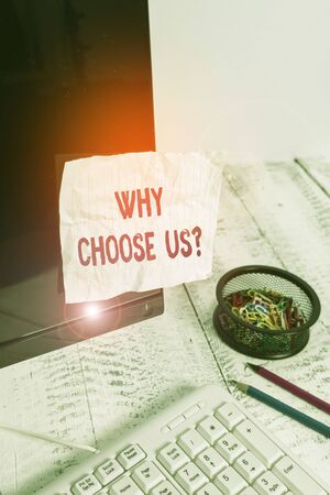 Text sign showing Why Choose Us Question. Business photo showcasing list of advantages and disadvantages to select product service Note paper taped to black computer screen near keyboard and stationaryの写真素材