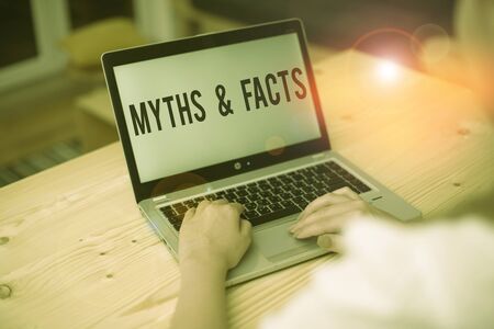 Writing note showing Myths And Facts. Business concept for usually traditional story of ostensibly historical events woman with laptop smartphone and office supplies technologyの写真素材