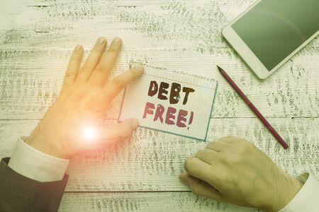 Conceptual hand writing showing Debt Free. Concept meaning does not owning any money to any individual or companies Hand hold note paper near writing equipment and smartphoneの写真素材