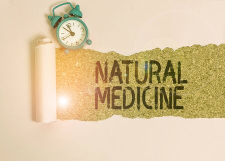 Text sign showing Natural Medicine. Business photo showcasing any of various systems of healing or treating disease Alarm clock and torn cardboard placed above a wooden classic table backdropの写真素材