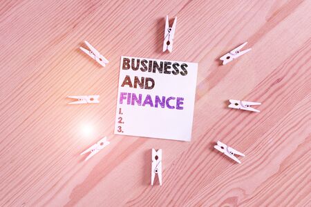 Word writing text Business And Finance. Business photo showcasing Management of Asset Money and Fund of a company Colored clothespin papers empty reminder wooden floor background officeの写真素材