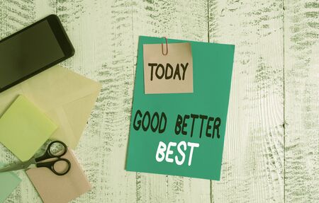 Writing note showing Good Better Best. Business concept for Increase quality Improvement Achievement Excellence Envelope paper sheet smartphone notepads scissors wooden backgroundの写真素材