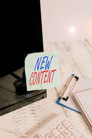 Conceptual hand writing showing New Content. Concept meaning fresh valuable and relevant information or context of a document Note paper taped to black screen near keyboard stationaryの写真素材