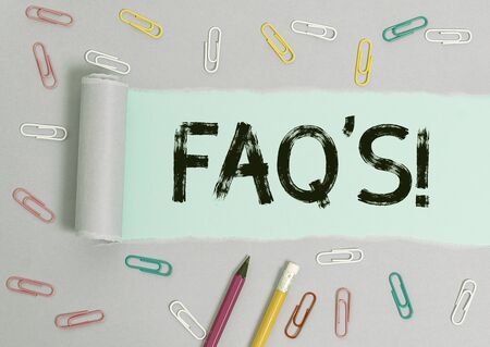 Writing note showing Faq. Business concept for a list of questions and answers relating to a particular subject Stationary and torn cardboard on a wooden classic table backdropの写真素材