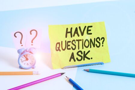 Text sign showing Have Questionsquestion Ask. Business photo text something that you say or write to ask a demonstrating Mini size alarm clock beside stationary placed tilted on pastel backdropの写真素材