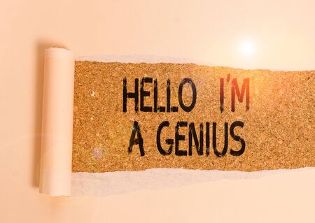 Conceptual hand writing showing Hello I M A Genius. Concept meaning Introduce yourself as over average demonstrating to others Cardboard which is torn placed above a wooden classic tableの写真素材