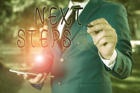 Conceptual hand writing showing Next Steps. Concept meaning numper of process going to be made after current one planning Businessman holds laptop and pen pointing into the copy spaceの写真素材