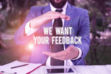 Conceptual hand writing showing We Want Your Feedback. Concept meaning to Improve Perforanalysisce or Product Timely Reaction Man in front of table. Mobile phone and notes on the tableの写真素材