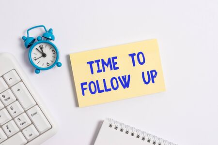 Conceptual hand writing showing Time To Follow Up. Concept meaning Enquiry of the previous task or information Continuation Keyboard with empty note paper and pencil white backgroundの写真素材