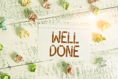 Handwriting text writing Well Done. Conceptual photo telling demonstrating that he made his task or job in perfect shape Crumpled colored rectangle square shaped paper reminder white wood deskの写真素材