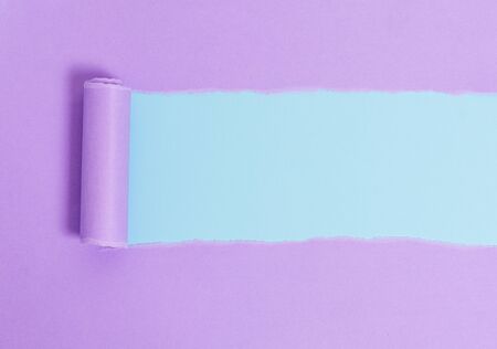 Cardboard which is torn in the middle placed above a plain table backdropの写真素材