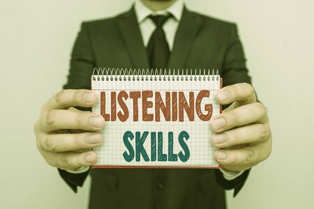 Writing note showing Listening Skills. Business concept for ability to understand information provided by the speaker Male human wear formal work suit with office look hold bookの写真素材