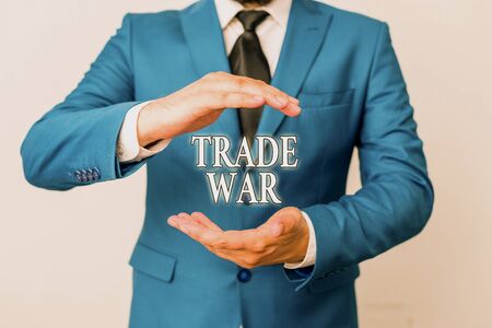 Conceptual hand writing showing Trade War. Concept meaning a situation in which countries try to damage each other s is trade Man in front of table. Mobile phone and notes on the tableの写真素材
