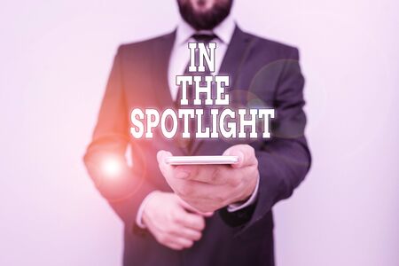 Text sign showing In The Spotlight. Business photo showcasing when crowd concentrating with individual demonstrating Male human wear formal work suit hold smart hi tech smartphone use one handの写真素材