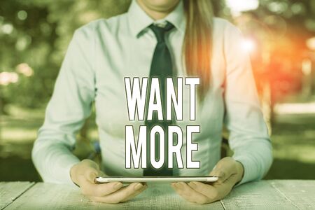 Writing note showing Want More. Business concept for Not having enough of something bigger challenges requirements Female business person sitting by table and holding mobile phoneの写真素材