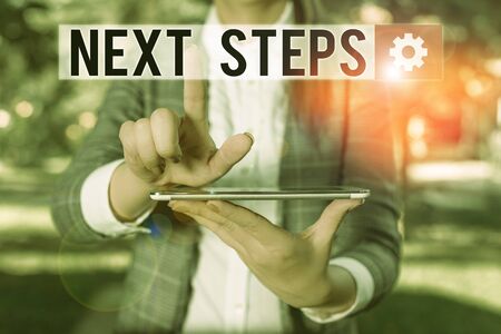 Text sign showing Next Steps. Business photo text numper of process going to be made after current one planning Outdoor scene with business woman holds lap top with touch screenの写真素材