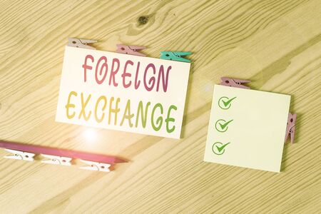 Word writing text Foreign Exchange. Business photo showcasing system for dealing in the currency of other countries Colored clothespin papers empty reminder wooden floor background officeの写真素材