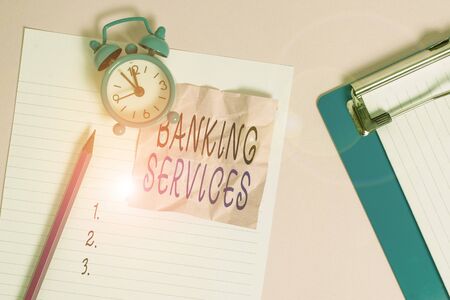 Handwriting text writing Banking Services. Conceptual photo tools for analysisaging demonstratingal finances and building assets Paper sheet note clipboard pencil vintage alarm clock colored backgroundの写真素材