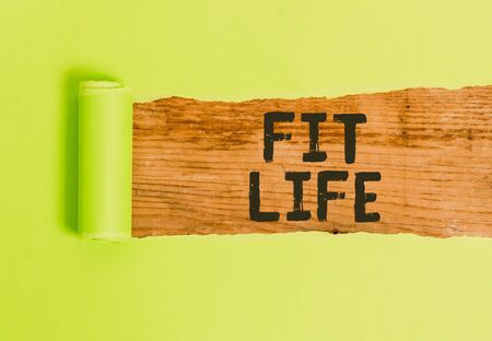 Word writing text Fit Life. Business photo showcasing maintaining a healthy weight with diet and exercise Healthy living Cardboard which is torn in the middle placed above a wooden classic tableの写真素材