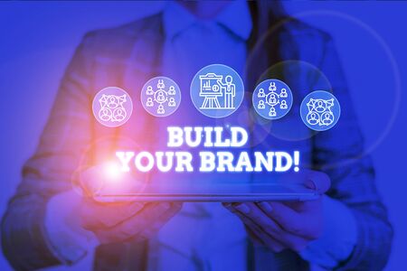 Conceptual hand writing showing Build Your Brand. Concept meaning creates or improves customers knowledge and opinions of product Woman wear work suit presenting presentation smart deviceの写真素材