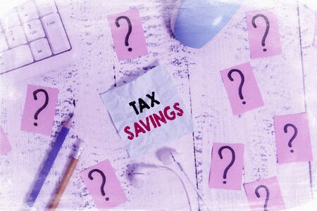 Writing note showing Tax Savings. Business concept for only a portion of income is taxable Pay a reduced amount of tax Writing tools and scribbled paper on top of the wooden tableの写真素材