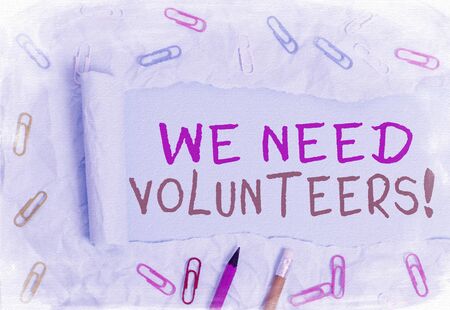 Conceptual hand writing showing We Need Volunteers. Concept meaning someone who does work without being paid for it Stationary and torn cardboard on a plain pastel table backdropの写真素材