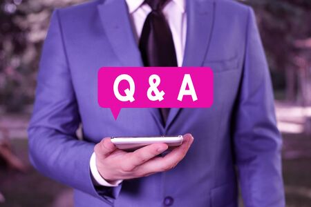 Text sign showing Q And A. Business photo text defined as questions being asked and answers Businessman in blue suite stands with mobile phone in handsの写真素材