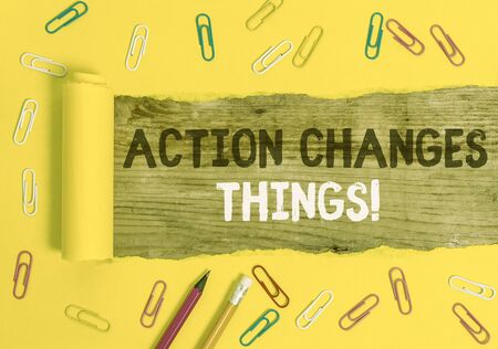 Handwriting text writing Action Changes Things. Conceptual photo start doing something against problem resolve or achieve it Stationary and torn cardboard placed above a wooden classic table backdropの写真素材