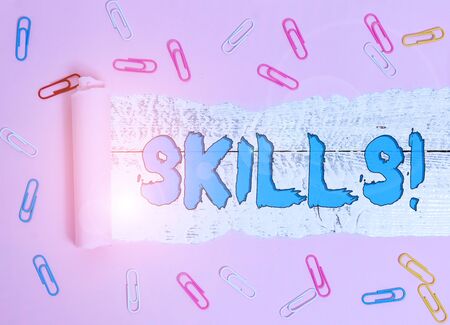 Conceptual hand writing showing Skills. Concept meaning ability do something very well by nature Paper clip and torn cardboard on wood classic table backdropの写真素材