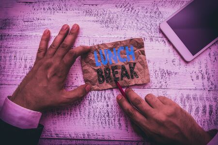 Conceptual hand writing showing Lunch Break. Concept meaning time when a demonstrating stops working or studying to have lunch Hand hold note paper near writing equipment and smartphoneの写真素材