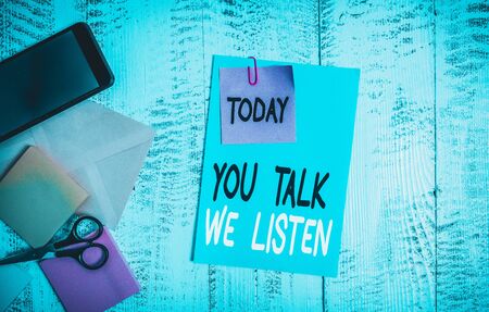 Writing note showing You Talk We Listen. Business concept for Two Way Communication Motivational Conversation Envelope paper sheet smartphone notepads scissors wooden backgroundの写真素材